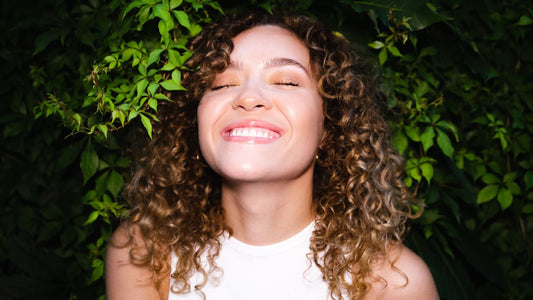 Cette photo présente une femme aux cheveux frisés qui va réaliser un lissage brésilien pour obtenir des cheveux lisses et en bonne santé grâce à cette technique de coiffure efficace et pratique.