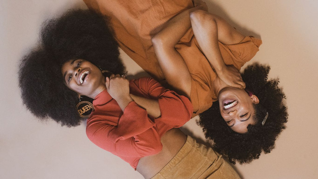 cette photo montre deux femmes au cheveux crépus qui pourront réaliser un lissage brésilien pour obtenir des cheveux doux et brillants.