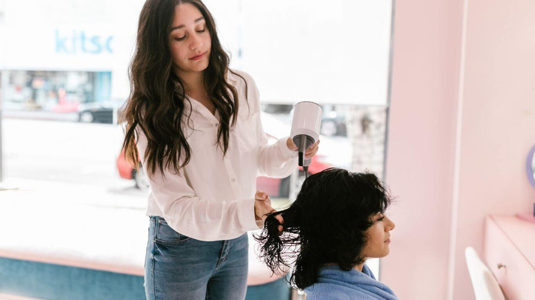 Cette photo montre une coiffeuse en train de réaliser un lissage brésilien sur une cliente. On peut voir les produits de lissage et le fer à lisser utilisés pour obtenir un résultat professionnel et durable.